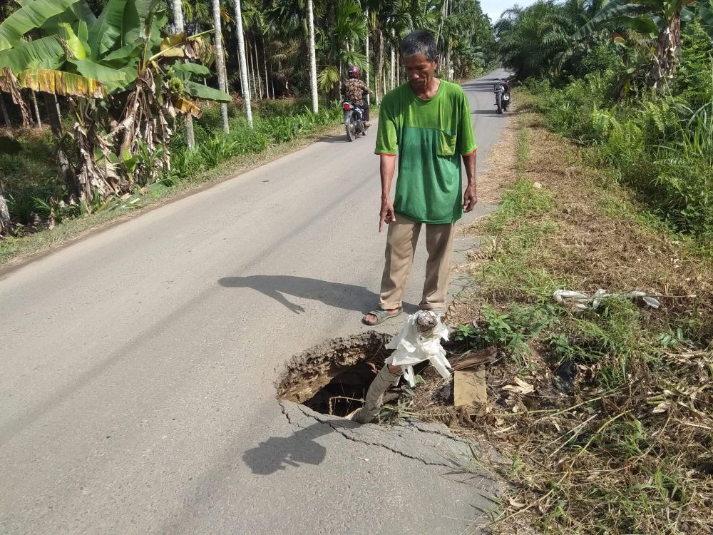 Lubang yang menganga di jalan lintas Teluk Serdang .
