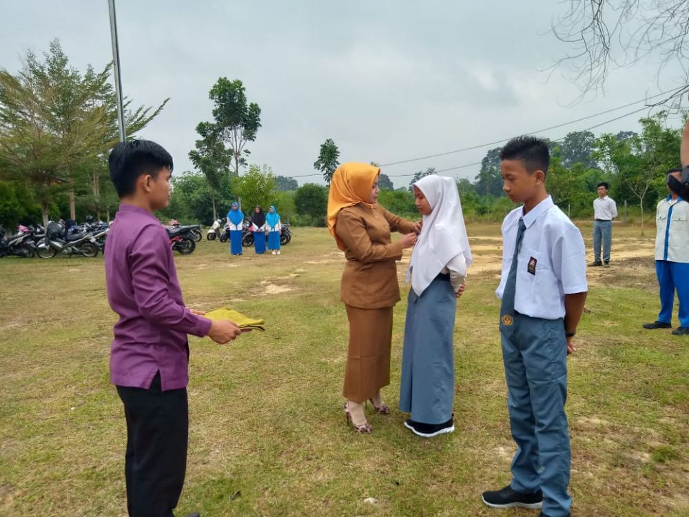 Kepsek SMKN 7 Tebo Ramayani, M.Pd menyematkan tanda peserta kepada siswa baru peserta MPLS.