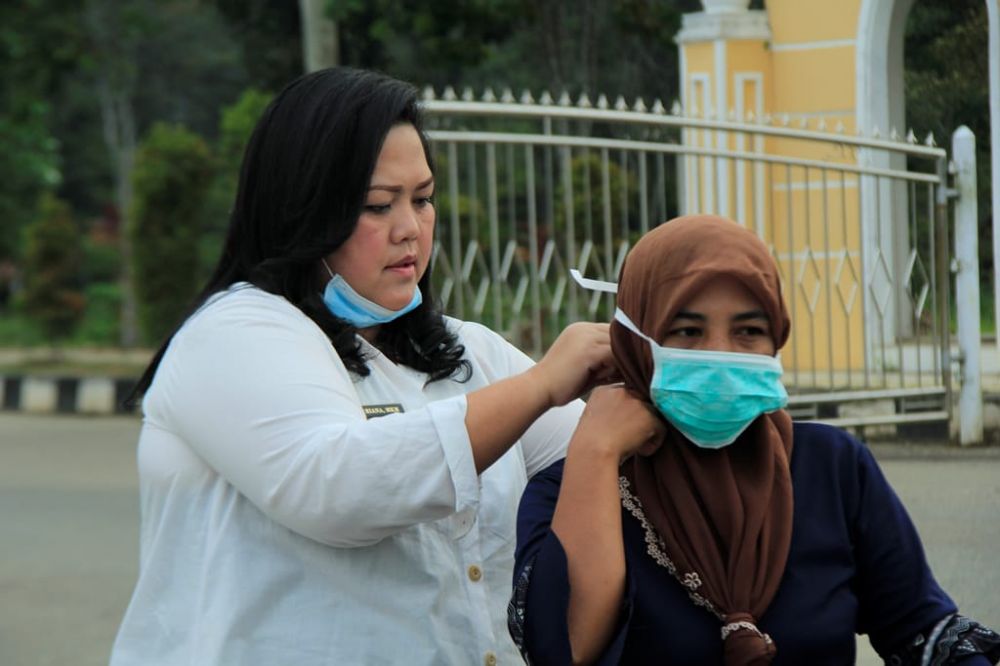 Kadinkes Tebo, Dr Riana Elizabeth memasangkan masker kepada salah seorang pengendara motor yang melintas dikomplek perkantoran Bupati Tebo