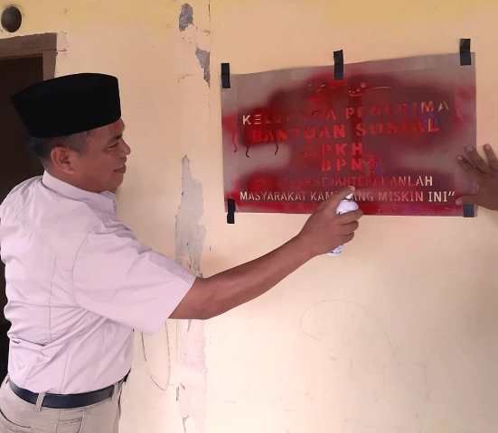 Kadis Sosial Sarolangun, H Juddin ketika memasangkan label BPNT dan PKH di dinding rumah KPM