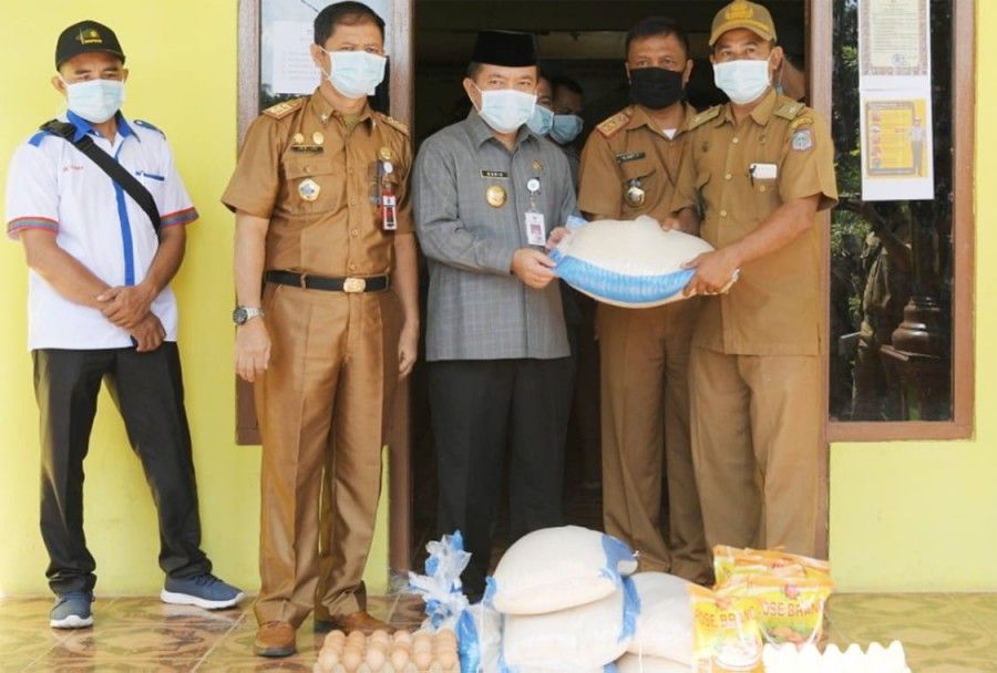 Bupati Al Haris menyerahkan bantuan beras kepada keluarga tidak mampu yang terdampak Corona