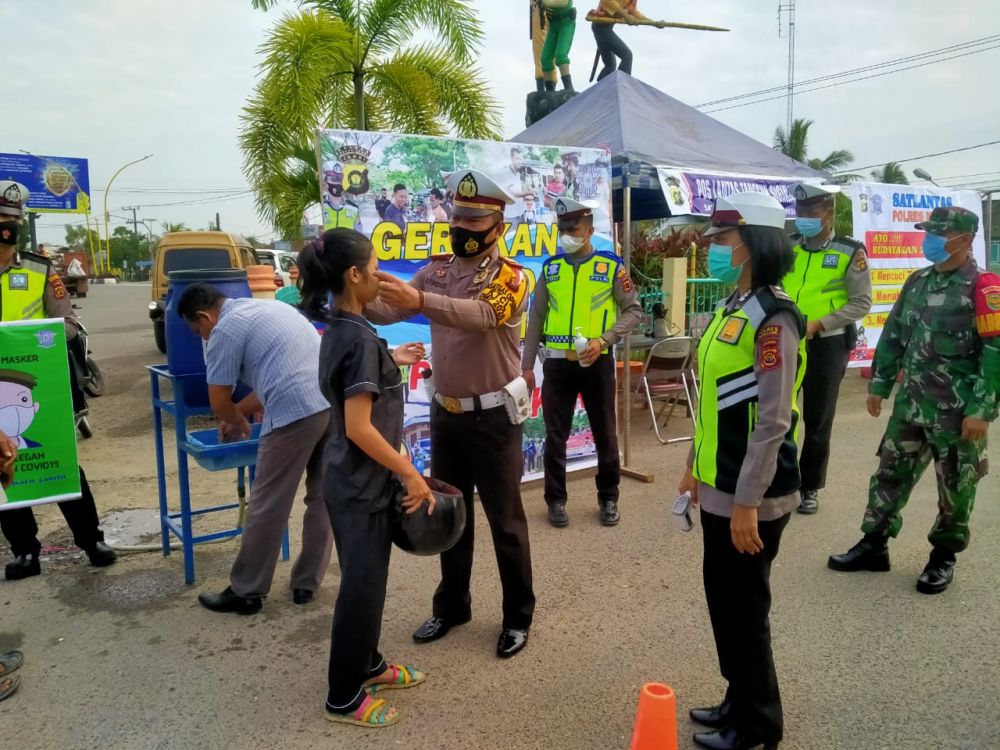Satlantas polres Muarojambi membagikan masker ke pengendara.
