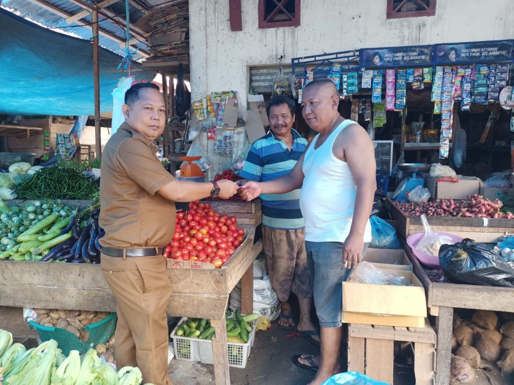Edi Sopyan saat menyerahkan uang ganti rugi kepada Zulkarnaen salah seorang pedagang di pasar Lebak Bungur Muaro Tebo