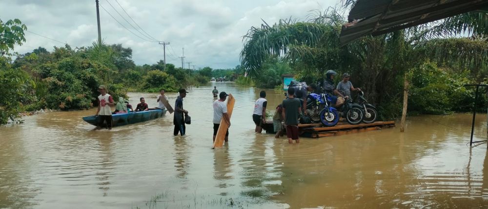 Warga terpaksa menggunakan rakit untuk menyebrangi jalan yang terendam banjir menuju jembatan penampuyan di Bungkal Kelurahan Muaro Tebo